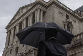 A commuter walks through heavy rain near the Bank of England, London.