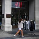 Retail workers move rails of clothes past a H&M store on Oxford Street.