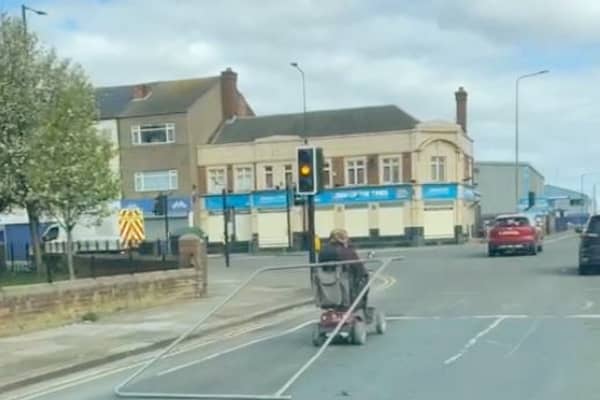 A man tows a metal fence from his mobility scooter in Grimsby. The man was spotted dragging the fence along as he stopped at traffic lights.