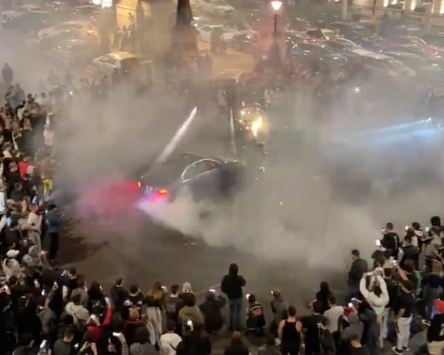 Crowds gather around car racers as they perform donuts in the early hours of the morning on Waterloo Place in central London, less than a mile from Buckingham Palace.