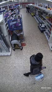 Video grab of Nicolae Boia crouched behind a trolley and filling his bag with unpaid for goods.