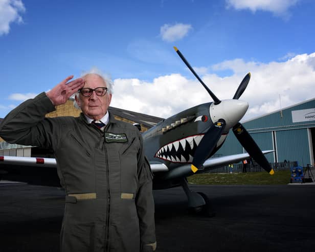 Alan Taylor standing in front of a Spitfire aircraft while saluting