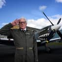 Alan Taylor standing in front of a Spitfire aircraft while saluting