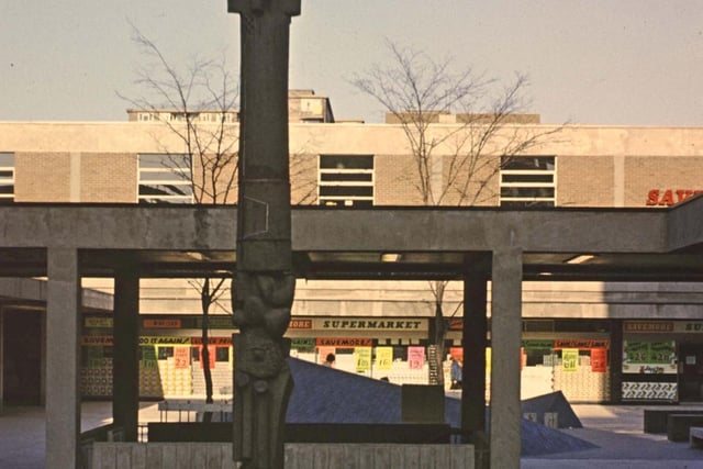 Queen's Parade looking towards Queen's Court in the late 1960s.  A totem pole stands tall in the middle. Savemore supermarket can be seen in the background.