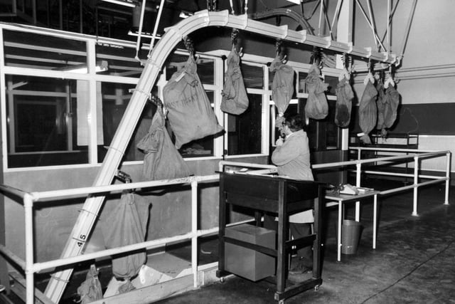 Incoming bags of mail are checked in as they enter the third floor mechanised section on a chain conveyor. The officer uses a tape recorder to note the arrivals.
