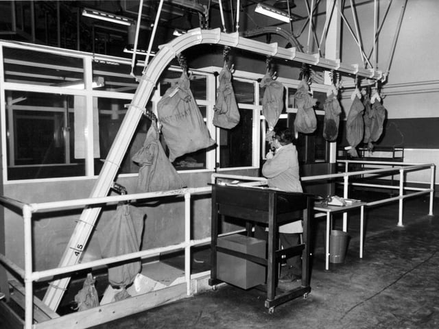 Incoming bags of mail are checked in as they enter the third floor mechanised section on a chain conveyor. The officer uses a tape recorder to note the arrivals.