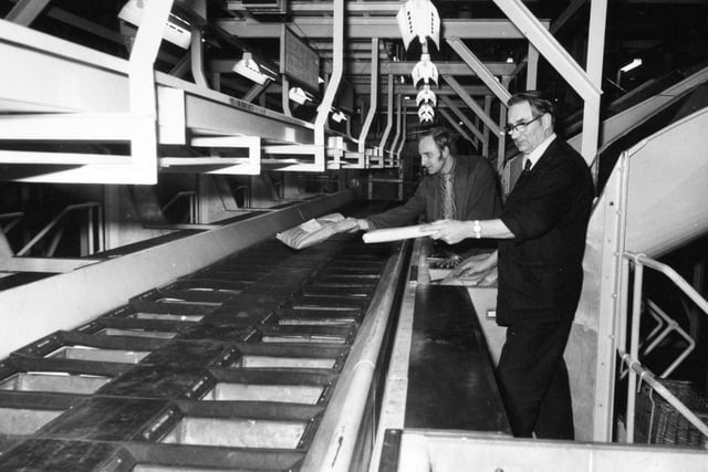 Staff sort outward bound packets into a fitting on the third floor of the mechanised complex. The packets are automatically cleared and taken by conveyor down to the first floor for sorting into smaller geographical areas.