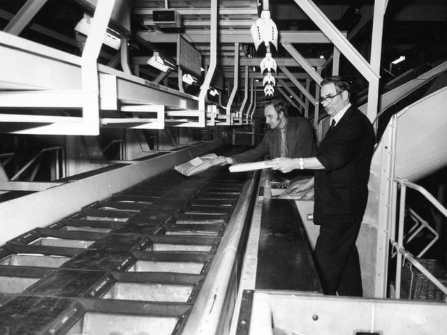 Staff sort outward bound packets into a fitting on the third floor of the mechanised complex. The packets are automatically cleared and taken by conveyor down to the first floor for sorting into smaller geographical areas.