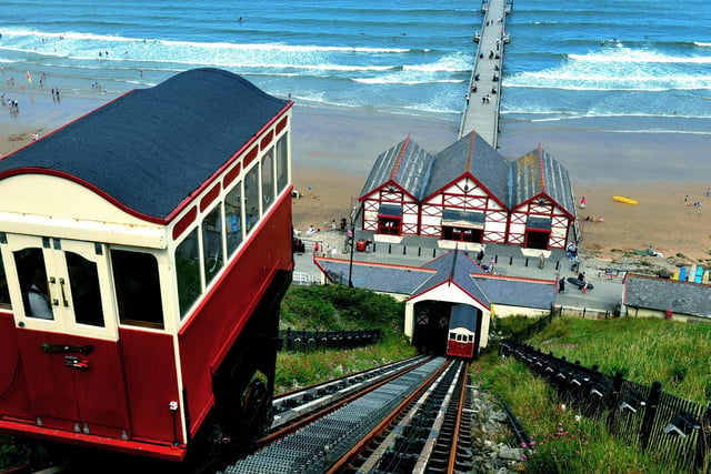 The Saltburn cliff tramway  at Saltburn by the Sea working up and down the cliff, with people dotted on the sands.