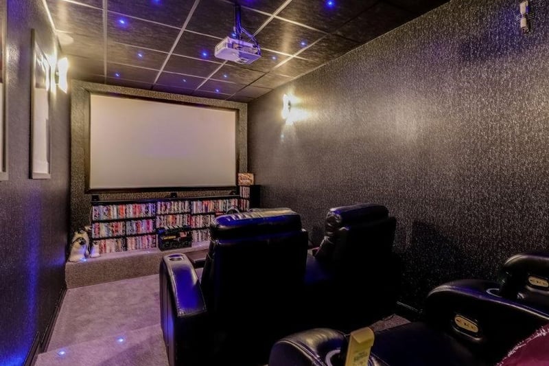 A fantastic cinema room with a tiered floor, suspended ceiling, feature LED lighting to the ceiling and floor and a Bose surround sound system.