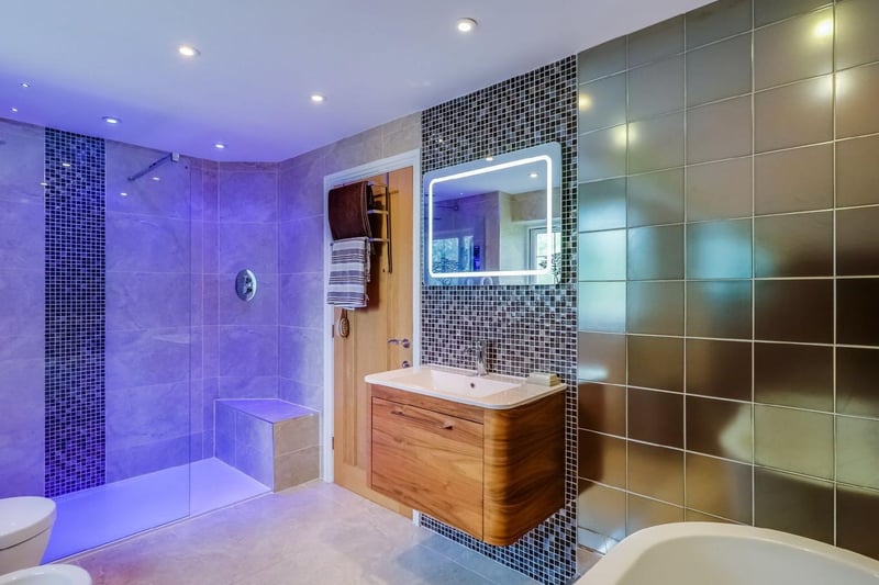 A spacious, luxury bathroom with a high quality suite which includes a freestanding bath and a large walk-in shower enclosure with rain water effect head.