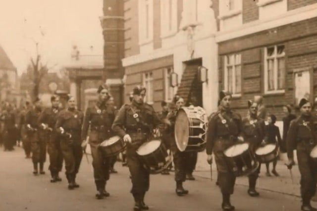 A band marches down Grove Road past the Town Hall and Police Station