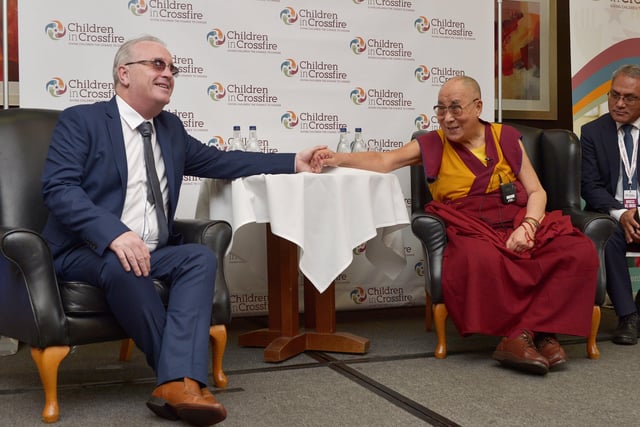 Richard Moore and the Tibetan spiritual leader the Dalai Lama hold hands at the City Hotel press conference in 2017. The Dalai Lama is the patron of the Children in Crossfire charity, founded by Richard Moore. The visit to the city marked the organisation’s 20th anniversary. DER3717GS009