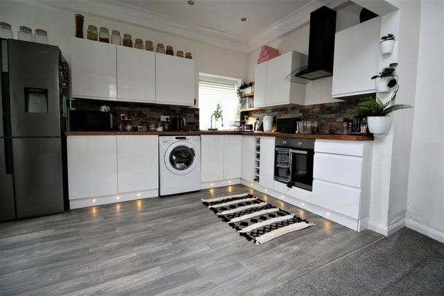 A section of the kitchen, that has fitted white gloss units with solid wood work surfaces.
