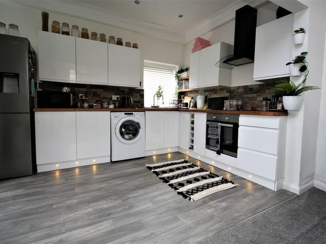 A section of the kitchen, that has fitted white gloss units with solid wood work surfaces.