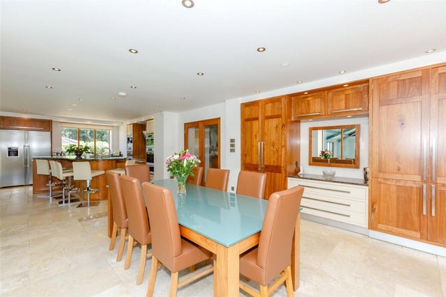 The spacious dining area features a range of matching built-in pantry cupboards and offers view out over the grounds, with French doors leading out into the front courtyard.