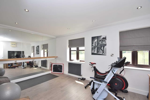The home gym benefits from hardwood floors and a full length mirror wall, and provides plenty of room for several machines and pieces of workout equipment.