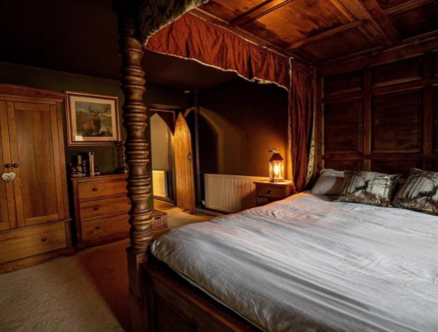 The roundhouse cottage features six handmade wooden four poster single beds each of which have red curtains and bed spreads and golden roman numerals etched on the front of their frames.
