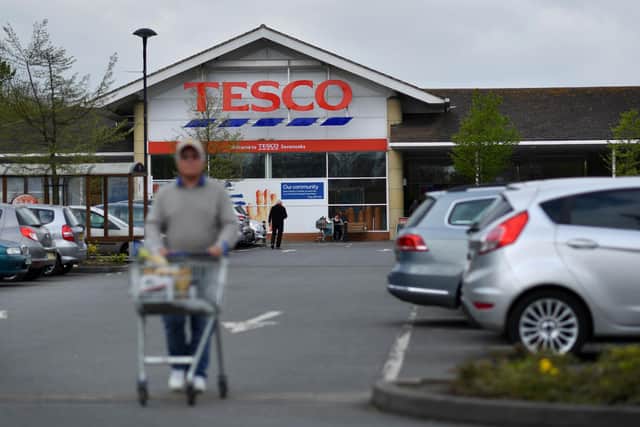 A customer pushes a shopping trolley as he walks through the car park of a Tesco (Photo credit should read BEN STANSALL/AFP via Getty Images)