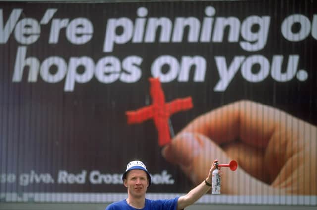 A Sheffield Wednesday supporter stands in front of an apt Red Cross poster before the FA Cup Final against Arsenal at Wembley in May 1993. Photo: Mike  Cooper/Allsport