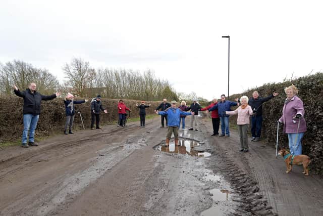 John Brown, Hatfield Parish Councillor, pictured on Hollin Bridge Road, with concerned residents. Picture: NDFP-23-02-21-PotHole 2-NMSY