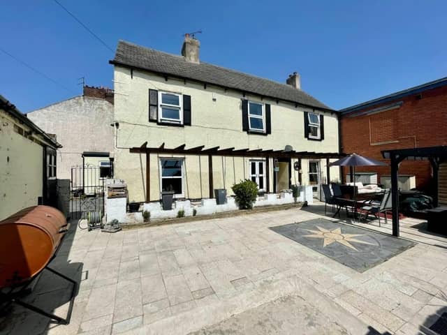 The front of the farmhouse, with patio area and bespoke bar to one side.
