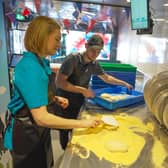 Earning their dough by preparing pizzas.