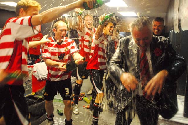 Rovers chairman John Ryan is showered with champagne by the playing squad