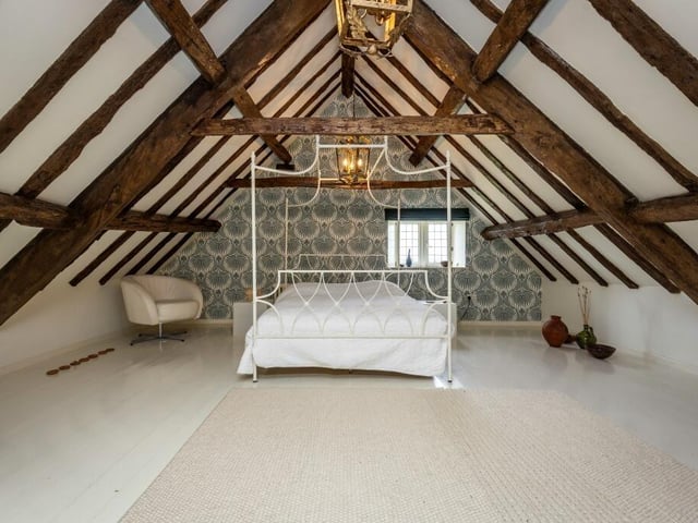 An upper floor bedroom with exposed beams.