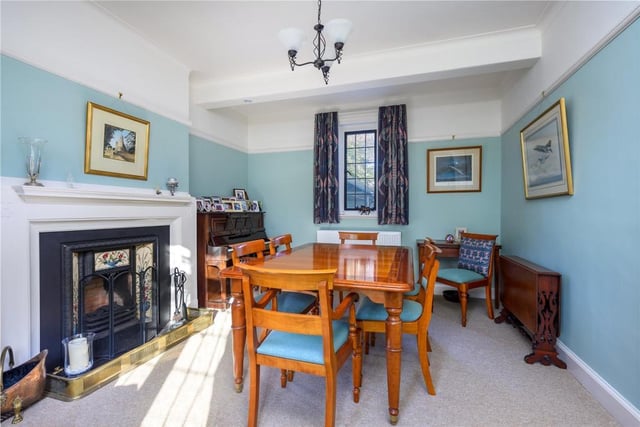 The dining room off the hall has windows on three sides and a Victorian style cast iron and tiled fireplace with gas fire.