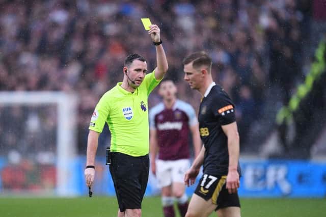 Referee Chris Kavanagh shows a yellow card to Emil Krafth of Newcastle United (Photo by Alex Burstow/Getty Images)