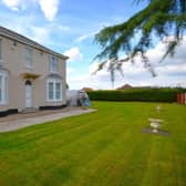 The impressive period property stands within extensive lawned gardens.