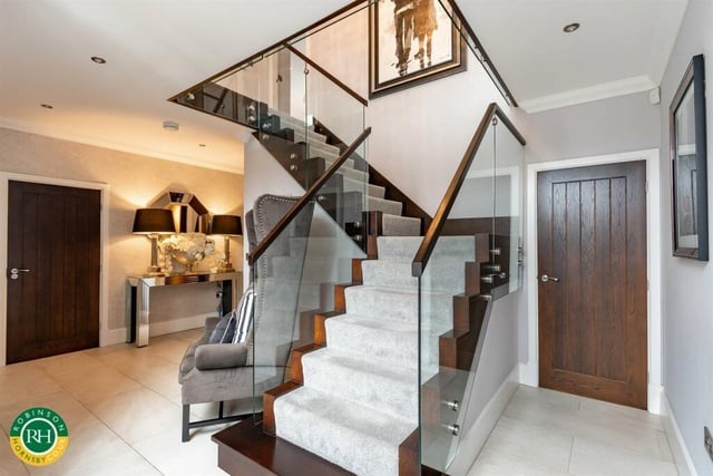 A feature staircase with glass balustrade leads up to a gallery landing.