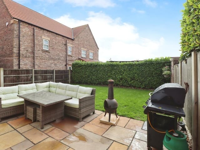 An enclosed lawned garden with patio seating area.