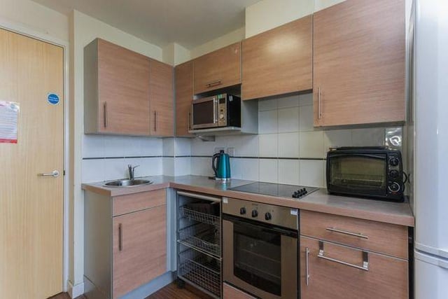 The fully fitted kitchen includes range of beech effect wall and floor units with complementary work surfaces over, stainless steel sink, integrated electric oven and hob and freestanding fridge freezer.