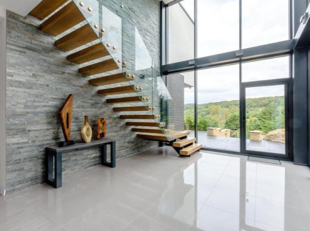 The large hallway is lit by natural light from the large windows which extend over two floors, and boasts a floating wooden staircase up to the first level.