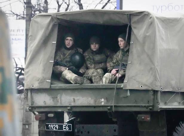 Ukrainian soldiers ride in a military vehicle in Mariupol, Ukraine, Thursday, Feb. 24, 2022. Russian troops launched their anticipated attack on Ukraine on Thursday, as President Vladimir Putin cast aside international condemnation and sanctions, warning other countries that any attempt to interfere would lead to "consequences you have never seen." (AP Photo/Sergei Grits)