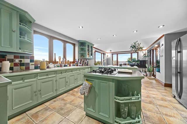 A stunning kitchen with sage-green wooden cabinetry also has a central island, and a farmhouse-style range cooker.