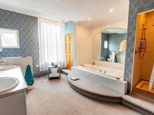 The luxurious main bathroom has a sunken bath, a shower cubicle, and twin wash basins within its suite.