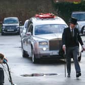 The funeral car makes its way to the chuch.