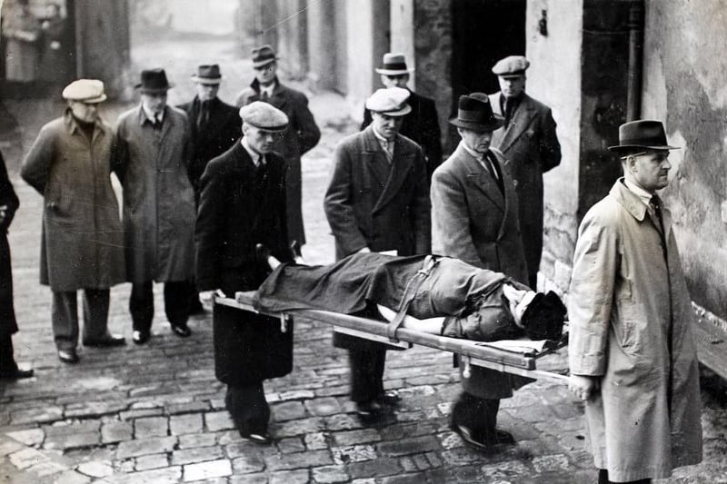 Emergency workers are pictured carrying the 'body' to an ambulance during the investigation of an arranged 'murder' at an old house in Doncaster as a training course for Doncaster police officers on 28th November 1938. The course included criminal law, crime investigation, scientific aids and other subjects of value to the officers.