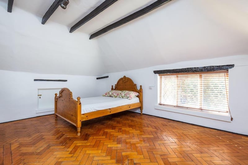A beamed bedroom with parquet flooring.