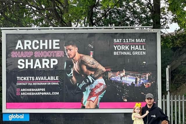 Archie Sharp, pictured with his family in front of an advert for an upcoming match.