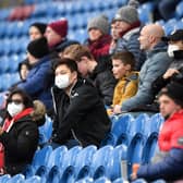 Fans wear disposable face masks prior to the Premier League match between Burnley FC and Tottenham Hotspur at Turf Moor.