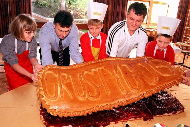 Conisbrough Balby Street Primary School head Ian Henderson (second left), baker Michael Harris and pupils, from left, Nicola Hattie, aged ten, Alex Cheswick, aged nine, and Christopher Lattimore, aged ten, put the Crusty Cob top on their giant jam sandwich.... October 1998