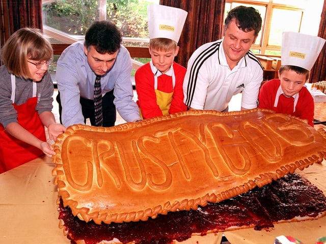 Conisbrough Balby Street Primary School head Ian Henderson (second left), baker Michael Harris and pupils, from left, Nicola Hattie, aged ten, Alex Cheswick, aged nine, and Christopher Lattimore, aged ten, put the Crusty Cob top on their giant jam sandwich.... October 1998