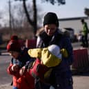 A woman walks with two children as Ukrainian refugees cross the Ukrainian-Romanian border in Siret, northern Romania, on March 19, 2022. - More than 3.3 million refugees have now fled Ukraine since the Russian invasion, the United Nations said on March 19, 2022, while nearly 6.5 million are thought to be internally displaced within the country. (Photo by Armend NIMANI / AFP) (Photo by ARMEND NIMANI/AFP via Getty Images)