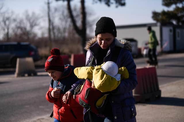 A woman walks with two children as Ukrainian refugees cross the Ukrainian-Romanian border in Siret, northern Romania, on March 19, 2022. - More than 3.3 million refugees have now fled Ukraine since the Russian invasion, the United Nations said on March 19, 2022, while nearly 6.5 million are thought to be internally displaced within the country. (Photo by Armend NIMANI / AFP) (Photo by ARMEND NIMANI/AFP via Getty Images)