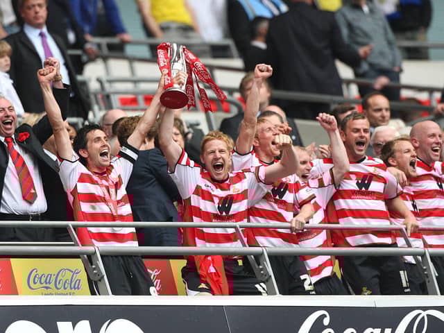 Rovers skipper Brian Stock lifts the play-off trophy with Adam Lockwood.