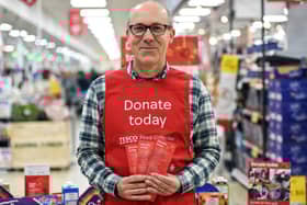 A Tesco volunteer holding a shopping list guide for donations at the launch of the Tesco Food Collection